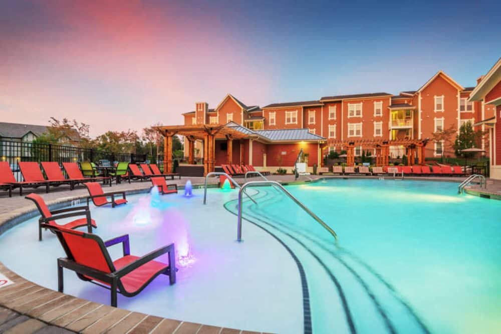 millenium one off campus apartments near the university of north carolina charlotte unc charlotte uncc resort style pool with swim up lounging deck at night
